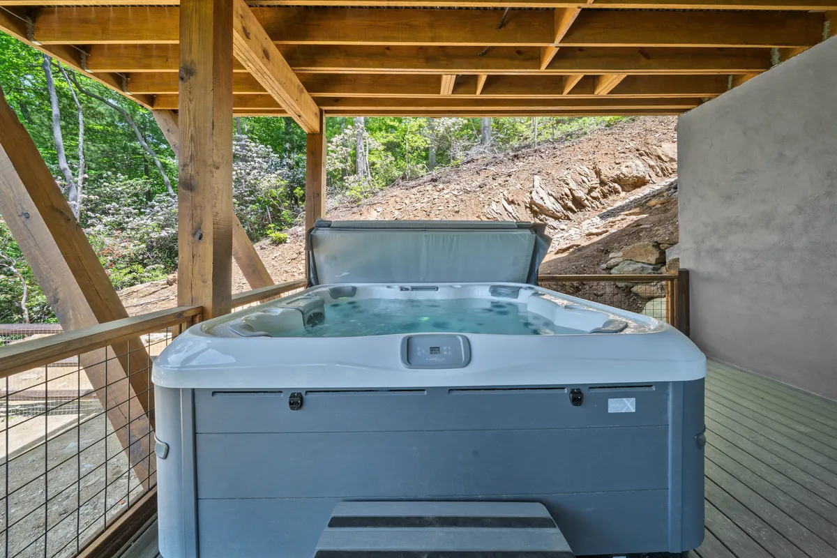 This image features an inviting outdoor hot tub framed by wooden beams and surrounded by lush natural scenery, evoking a sense of privacy, tranquility, and immersion in the mountain landscape.