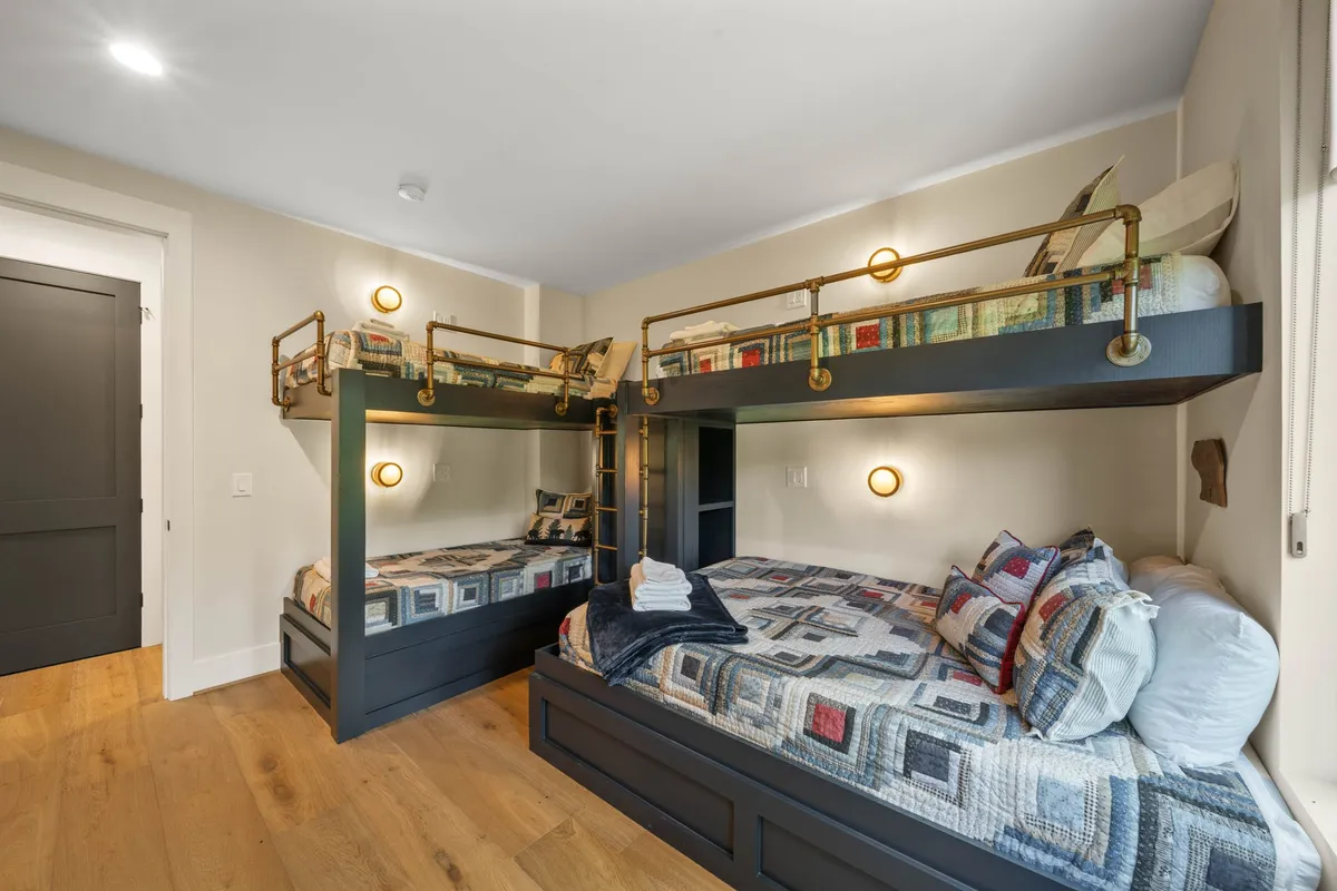 A cheerful bunk room with sturdy bunk beds, colorful bedding, and wall sconces. The playful design invites storytime and fun, making it an appealing space for kids or families sharing the room.