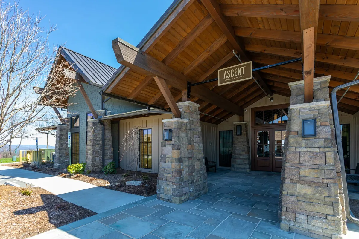 The entrance to the Ascent Wellness & Fitness Center, framed by sturdy stone columns and wooden beams, invites guests for massage services and holistic wellness experiences, signaling the availability of upscale amenities on site.