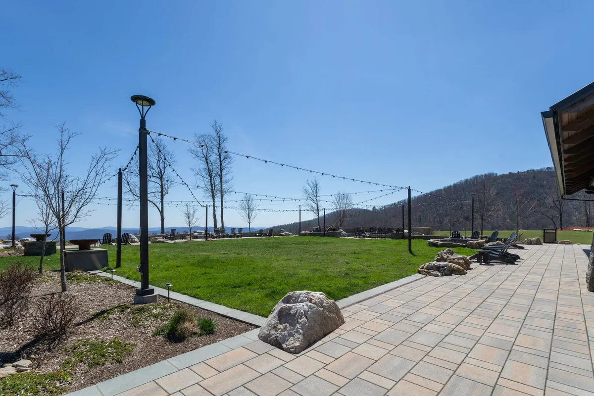 A relaxed, welcoming lawn area with string lights, a paved walkway, cozy seating, and expansive mountain views. The space is ideal for outdoor gatherings, family picnics, stargazing, and seasonal community events. The atmosphere is both festive and serene, easily capturing the spirit of open-air fun and communal enjoyment.